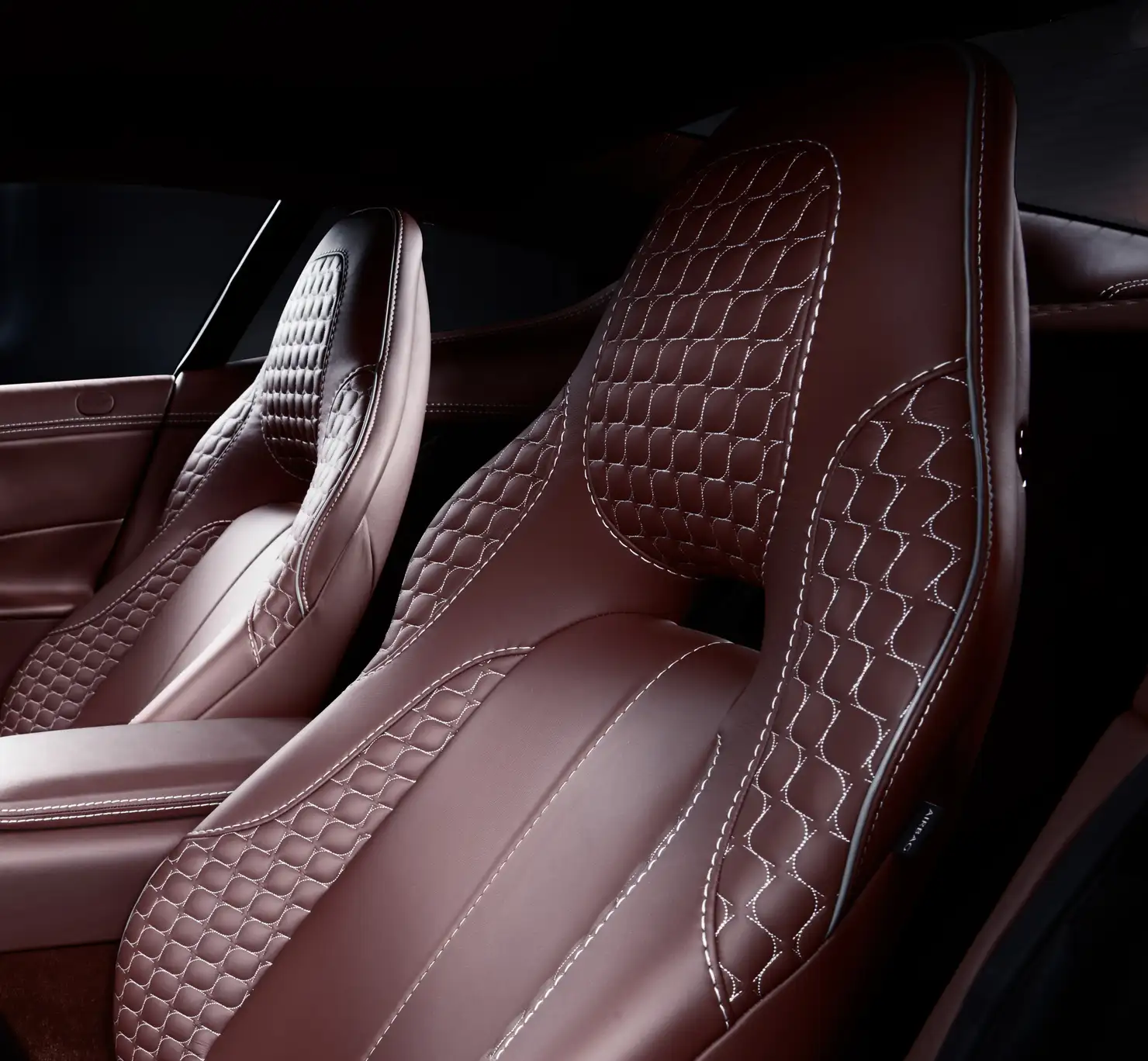 Burgundy leather car seats with quilted backrests and white contrast stitching