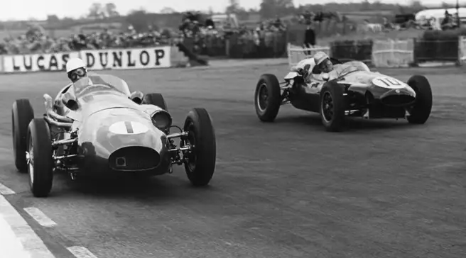 Black-and-white photograph of an Aston Martin DBR4 leading another single-seater through a bend in a 1959 race